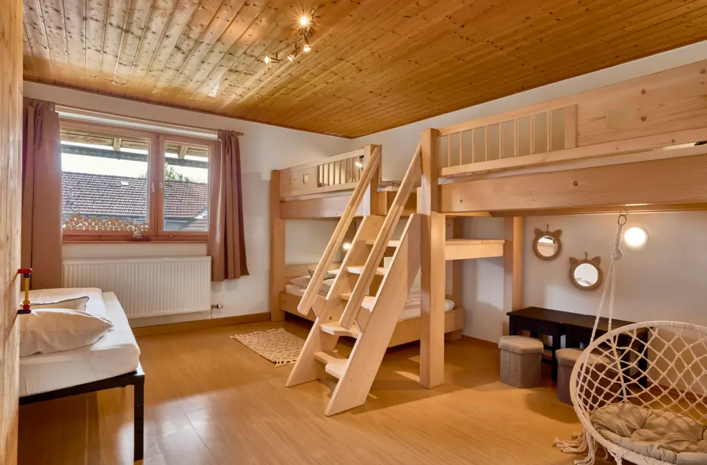 Kinderzimmer mit zwei Holzstockbetten und Hängesessel