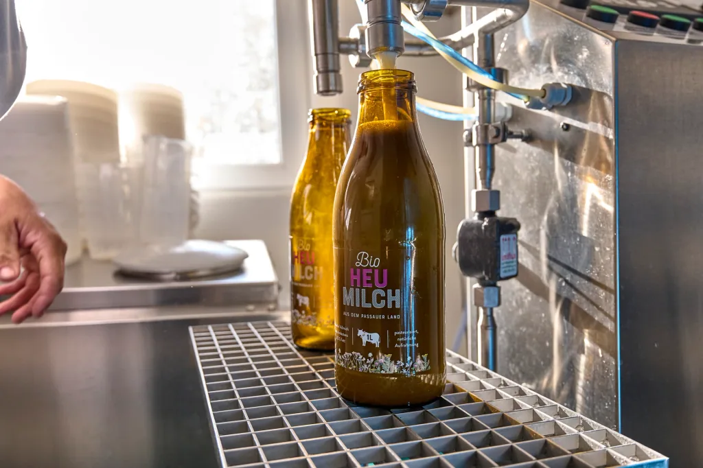 Eine Bio-Heumilchflasche wird an der Abfüllanlage in der Hofmolkerei befüllt