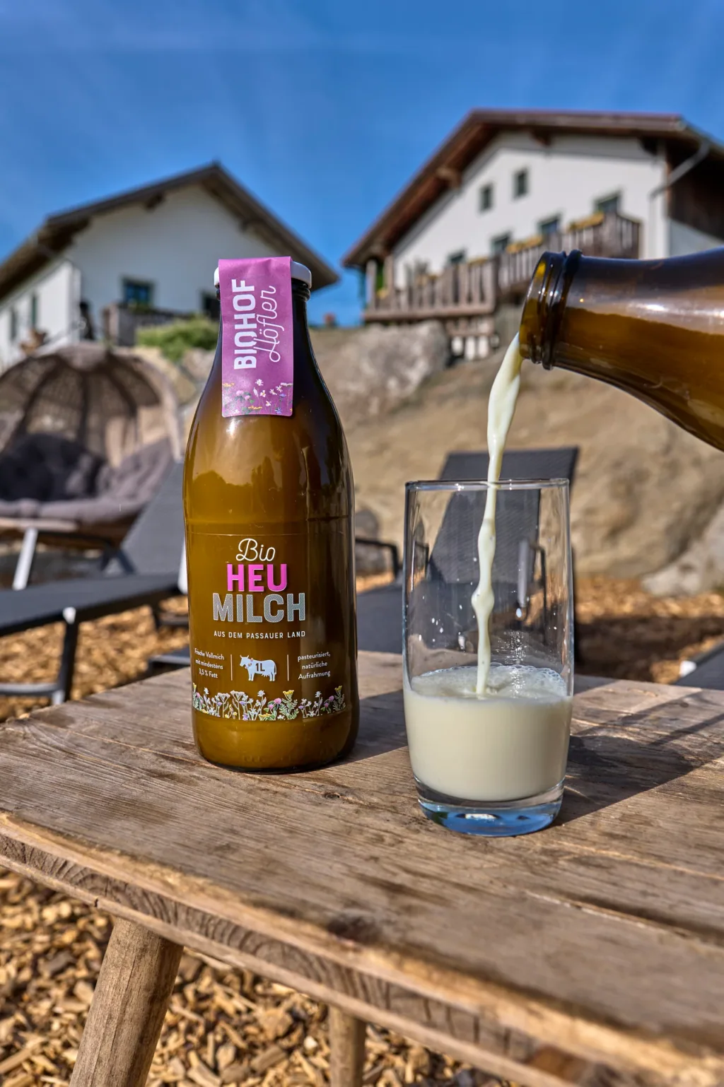 Bio-Heumilch wird auf der Hofterrasse in ein Glas eingeschenkt