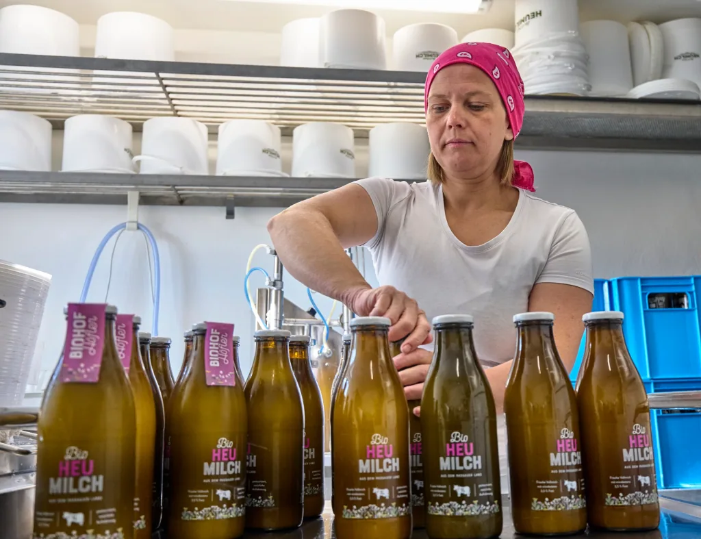 Eine Person verschließt eine Milchflasche zwischen weiteren Glasflaschen